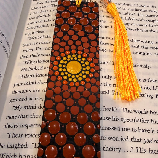 Decorative wooden beaded bookmark with a yellow tassel on an open book.