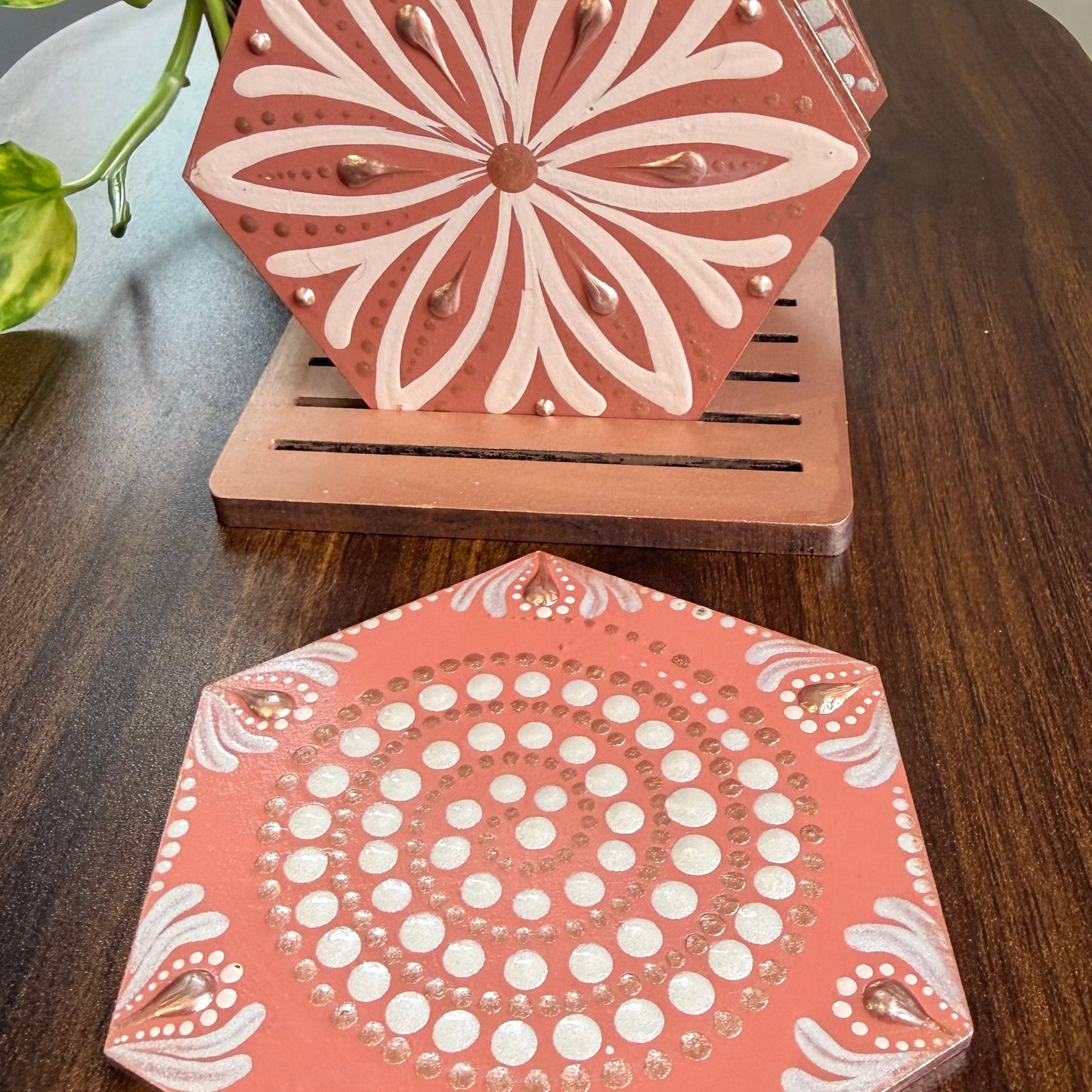 Hexagonal wooden coasters with white floral patterns on a wooden surface.
