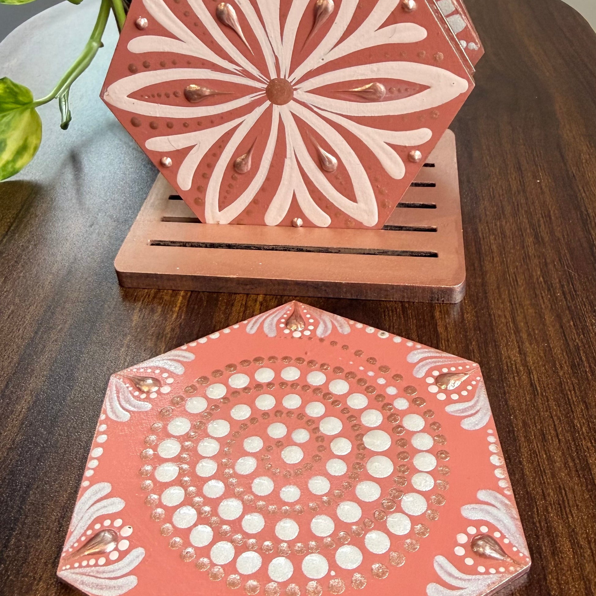 Hexagonal wooden coasters with white floral patterns on a wooden surface.