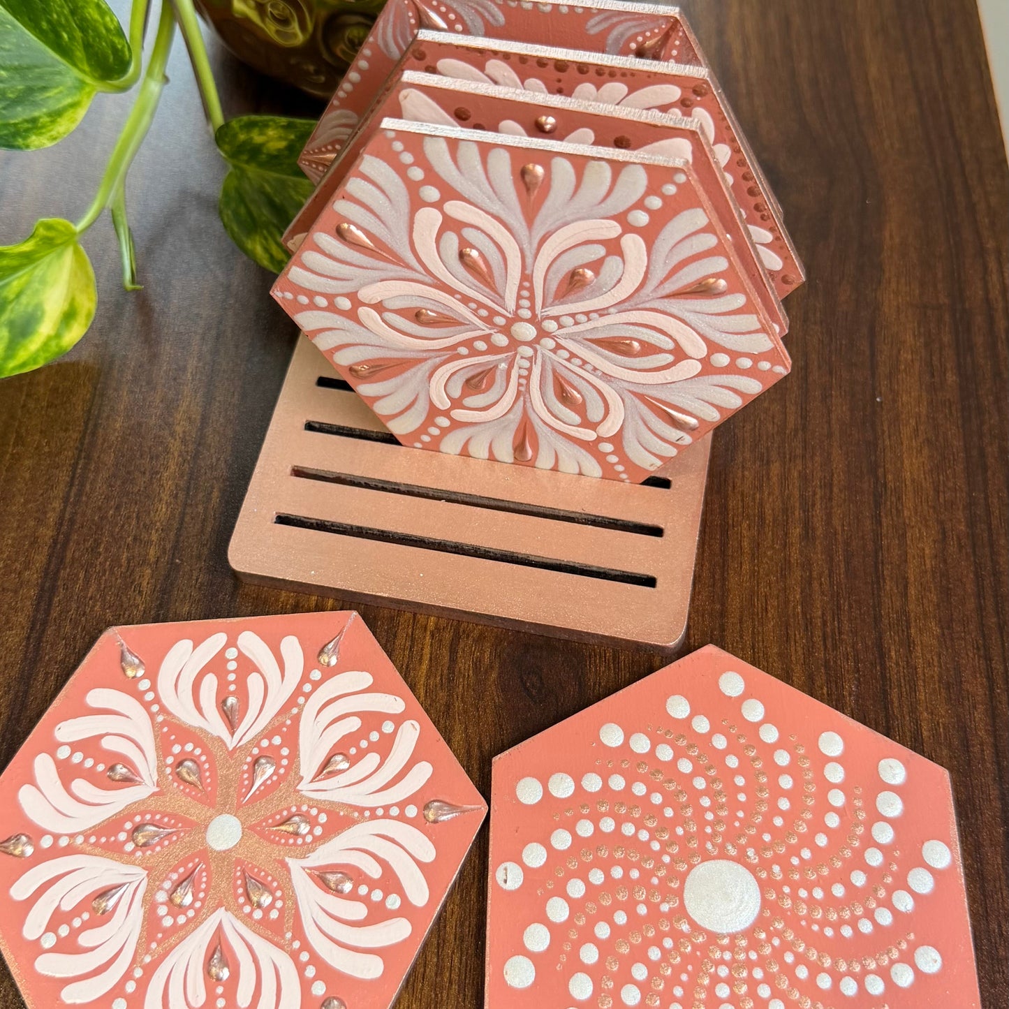 Hexagonal hand painted mandala coasters with floral patterns on a wooden surface.