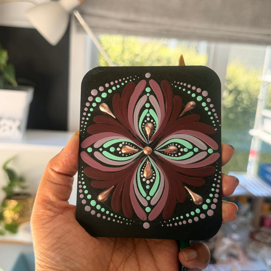 Hand holding a black case with a colorful floral design in an indoor setting