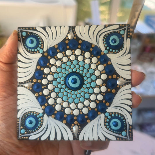 Hand holding a small square piece of art with a mandala design. Can be use as a table top mini mandala or fridge magnet