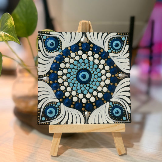 Small mandala painting on a wooden easel with a blurred background